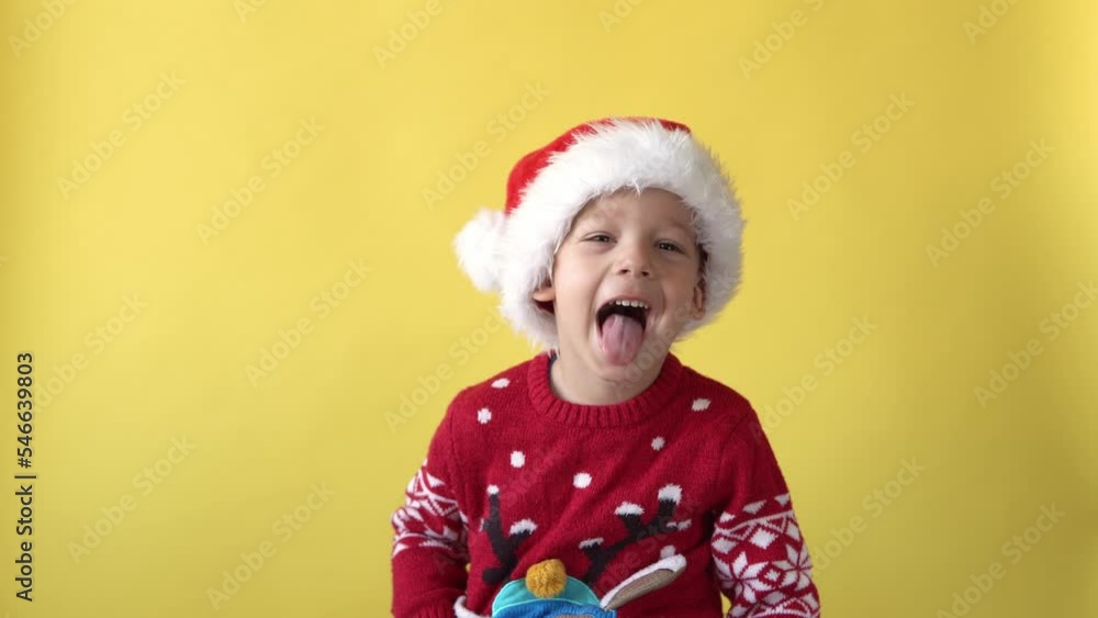 Portrait Emotion Cute Happy Cheerful Chubby Preschool Baby Boy Laughing Fooling Around in Santa Hat Looking On Camera At Yellow Background. Child Christmas Celebrate. Kid Have Fun Spend New Year Time Portrait Emotion Cute Happy Cheerful Chubby Preschool Baby Boy Laughing Fooling Around in Santa Hat Looking On Camera At Yellow Background. Child Christmas Celebrate. Kid Have Fun Spend New Year Time