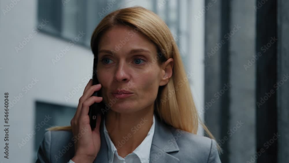 Close-up busy woman walking near office building talking on mobile phone professional businesswoman manager answering business call using smartphone remote communicate with client explains information Close-up busy woman walking near office building talking on mobile phone professional businesswoman manager answering business call using smartphone remote communicate with client explains information