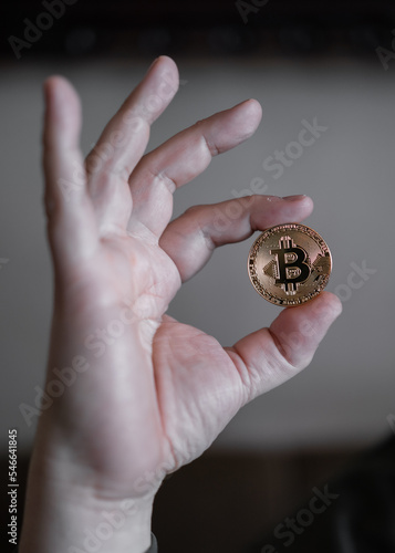 Hand holding and showing a golden Bitcoin