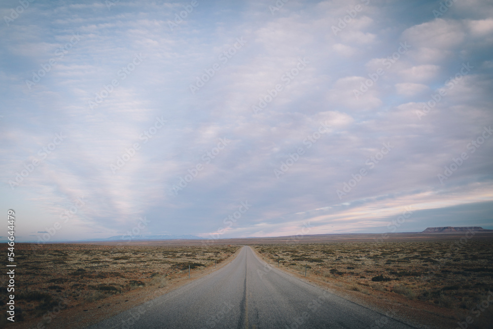The open road extends into the desert with a sunset sky. The open road extends into the desert with a sunset sky.
