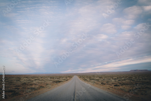 The open road extends into the desert with a sunset sky. photo