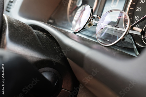 Glasses on the dashboard of a car. Accessory for drivers with vision problems. Road safety concept. © koldunova