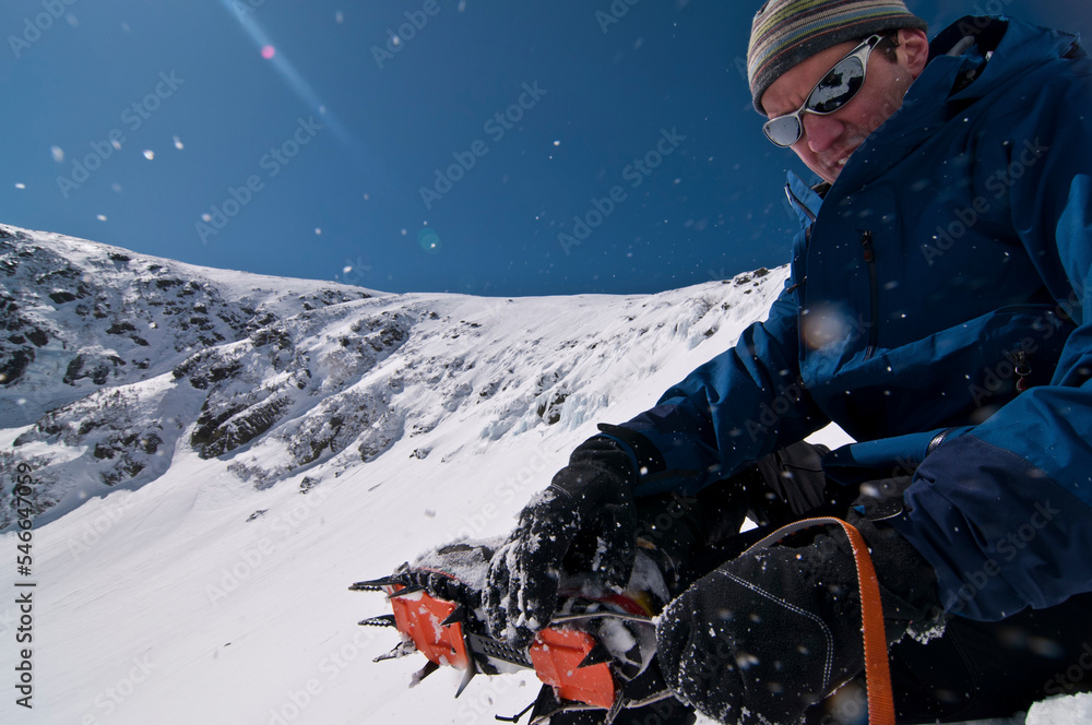 Man putting on crampons in the mountains Man putting on crampons in the mountains