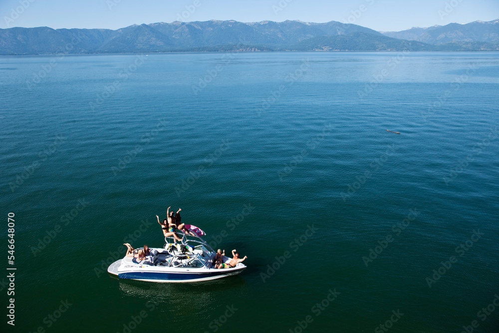 A aerial view of a group of young adults partying on a wakeboard boat on a lake in Idaho.