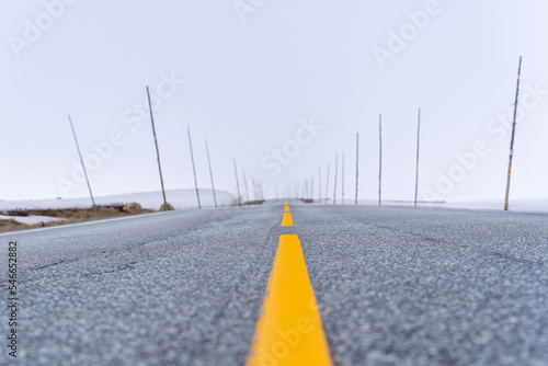 yellow bright line right in the middle of gray asphalt where we see a straight road in perspective