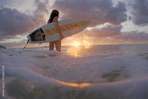 A young woman with a surfboard at sunrise on Blueys Beach, Australia. photo