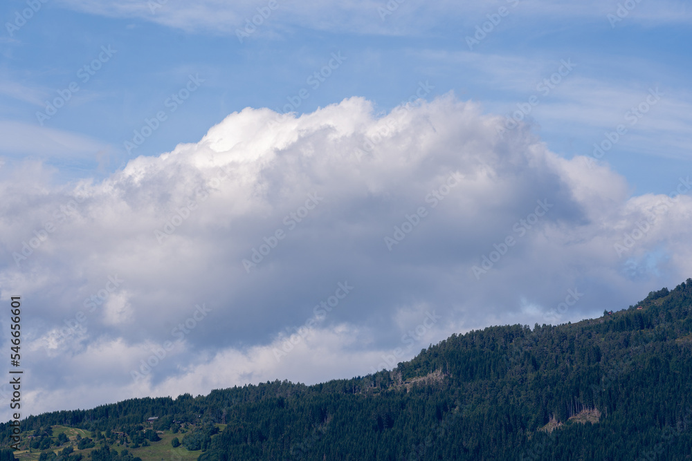 blue beautiful sky with various pale airy white clouds, under which are dark relief mountains