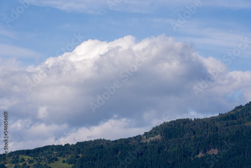 blue beautiful sky with various pale airy white clouds, under which are dark relief mountains