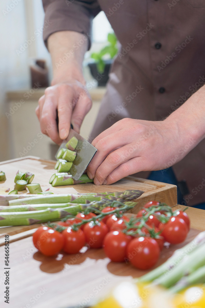Man cutting asparagus on wooden board Man cutting asparagus on wooden board