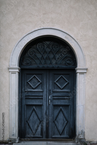 Elegant old double door entrance of building in Europe. Vintage wooden doorway and stucco fretwork wall of ancient stone house. Ornate grey wood door. Architecture in Poland. © Avalepsap