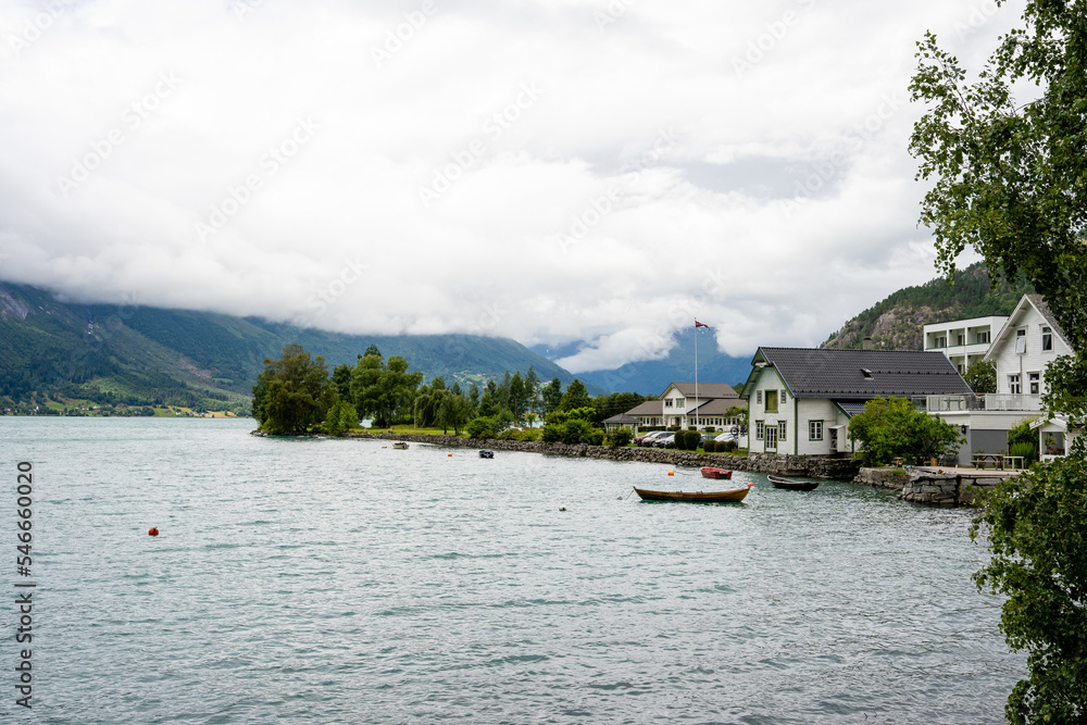 Fototapeta premium a fjord with blue water where there are small boats behind which there is a white big house on the shore