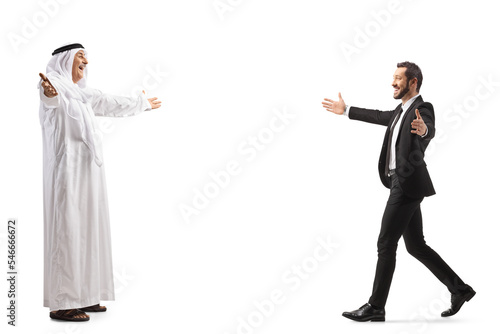 Full length profile shot of a mature arab man in a robe meeting a businessman