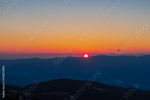 Scenic view of sun going up behind mountain Koralpe during sunrise seen from mountain peak Zingerle Kreuz, Saualpe, Lavanttal Alps, Carinthia, Austria, Europe. Soft red colored sky creating calm vibes photo