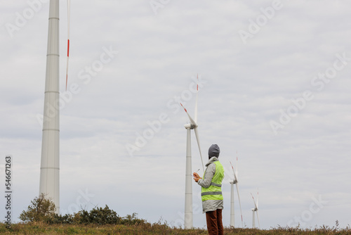 female engineer in a protective vest takes measurements of the speed of wind turbines. electricity is generated by wind. technologies without an eco trace. engineering solution. generating electricity