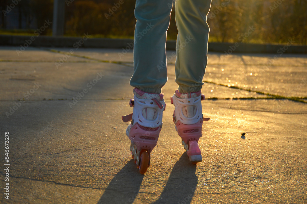 female legs in roller skates on a concrete pavement during sunset. evening workout or a walk in the fresh air. active lifestyle and sports