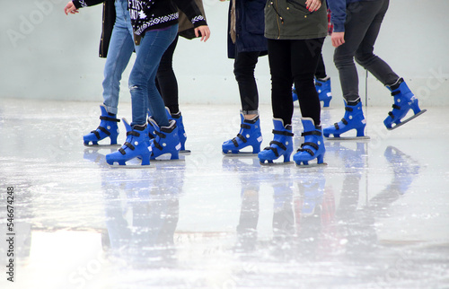 Ice skating youngsters on the skating rink in blue ice skates.