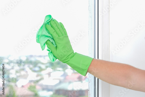 A man washes a glass window and a plastic frame with a folk remedy with household soap. Ecology.
