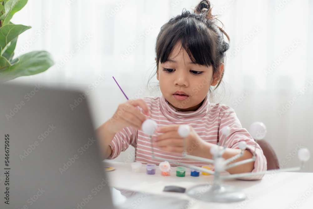 Asian Little girl studies the solar system in geography class. looking at the scale model of planets Asian Little girl studies the solar system in geography class. looking at the scale model of planets