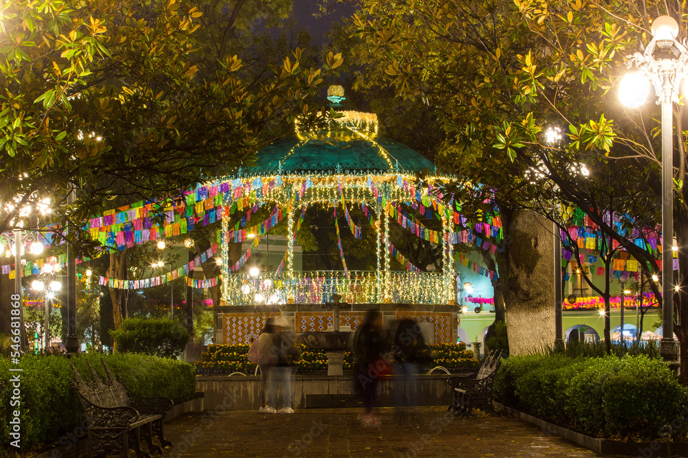 Beautiful night scene of a kiosk decorated with colorful lights for christmas and new year in Mexico, people walking around