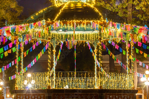 close shot of Beautiful night scene of a kiosk decorated with colorful lights for christmas and new year in Mexico, people walking around
