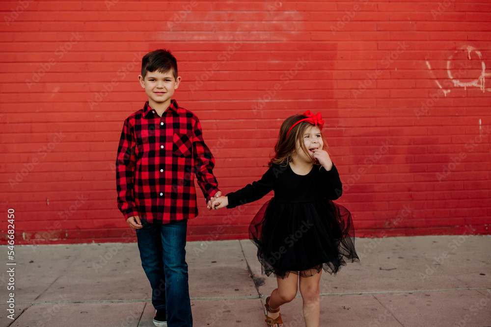 Portrait of brother and sister in front of red wall Portrait of brother and sister in front of red wall