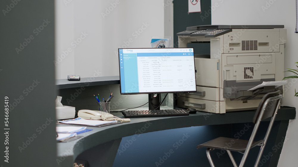 Reception counter in health center to make appointments on computer, giving medical support to patients. Empty hospital registration desk with report papers and checkup forms. Handheld shot. Reception counter in health center to make appointments on computer, giving medical support to patients. Empty hospital registration desk with report papers and checkup forms. Handheld shot.