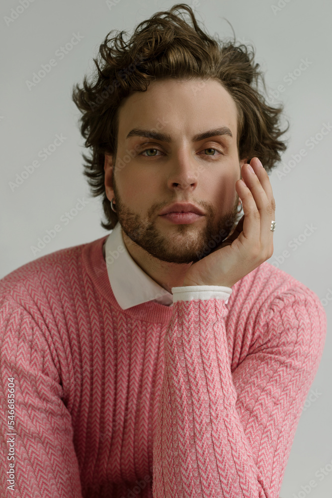 A handsome man with curly hair & high brow wearing a pink pullover A handsome man with curly hair & high brow wearing a pink pullover