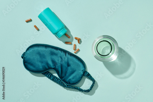 Pills and sleeping mask on pink background. Insomnia concept.
