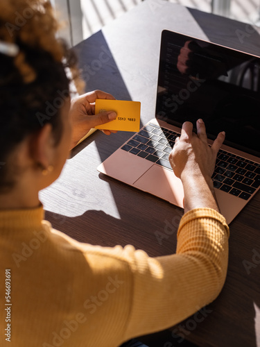 Crop woman entering credit card credentials into laptop photo