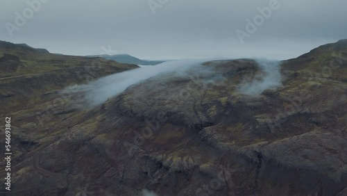 Soft clouds slowly moving across the highlands in Iceland. Mysterious fog and icredible volcanic landscape. Exploring powerful forces of nature. Cloudy grey blue evening light. Aerial view.  photo