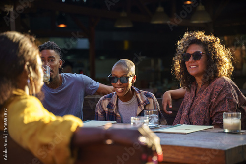 Friends sitting together at sunny table outside photo