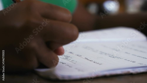 Close up of a person writing on the page of a paper workbook.