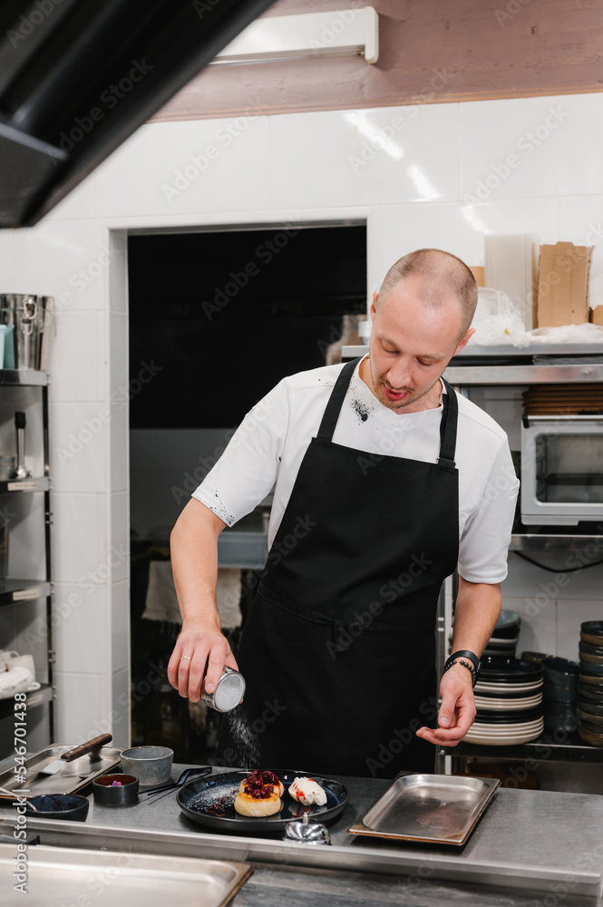 Male chef garnishing dessert with powdered sugar Male chef garnishing dessert with powdered sugar