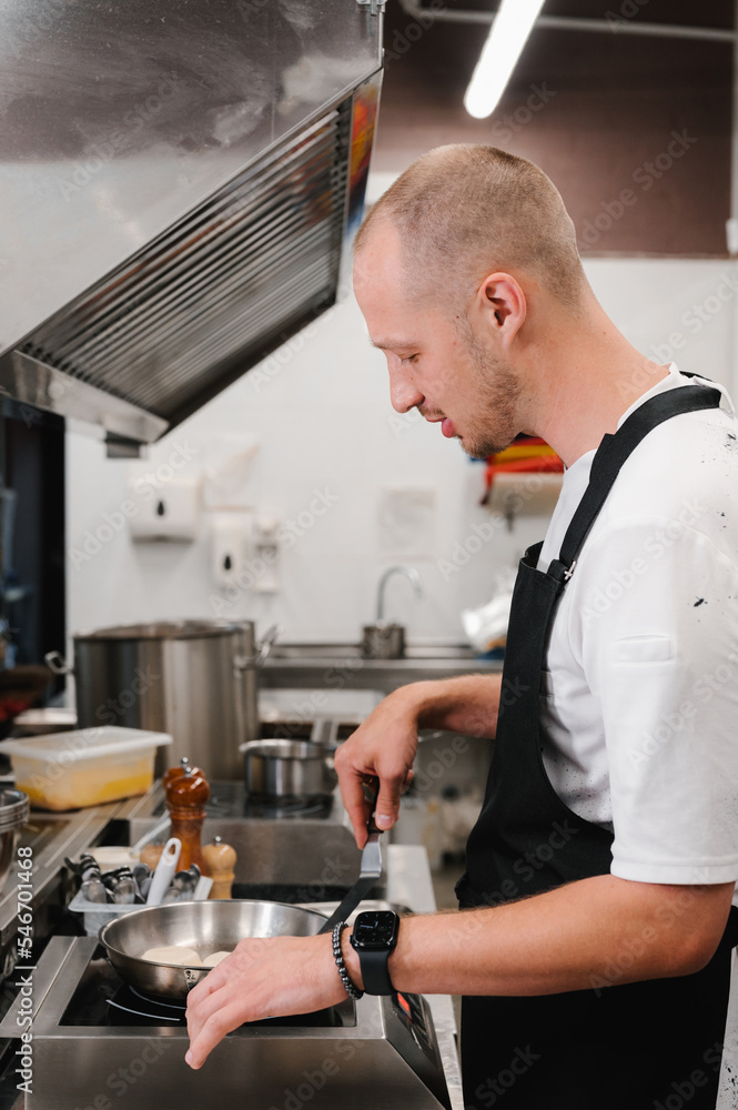 Male chef putting syrniki on tray Male chef putting syrniki on tray