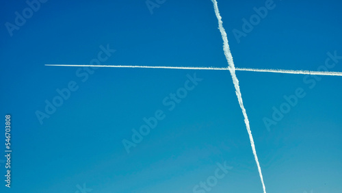 Two crossing contrails. Airplane trails across clear blue sky,