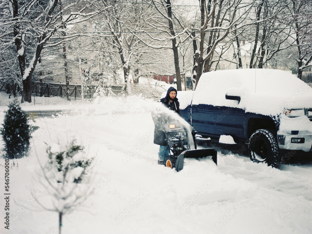 man clearing heavy snow in winter in his driveway with a snowblower man clearing heavy snow in winter in his driveway with a snowblower