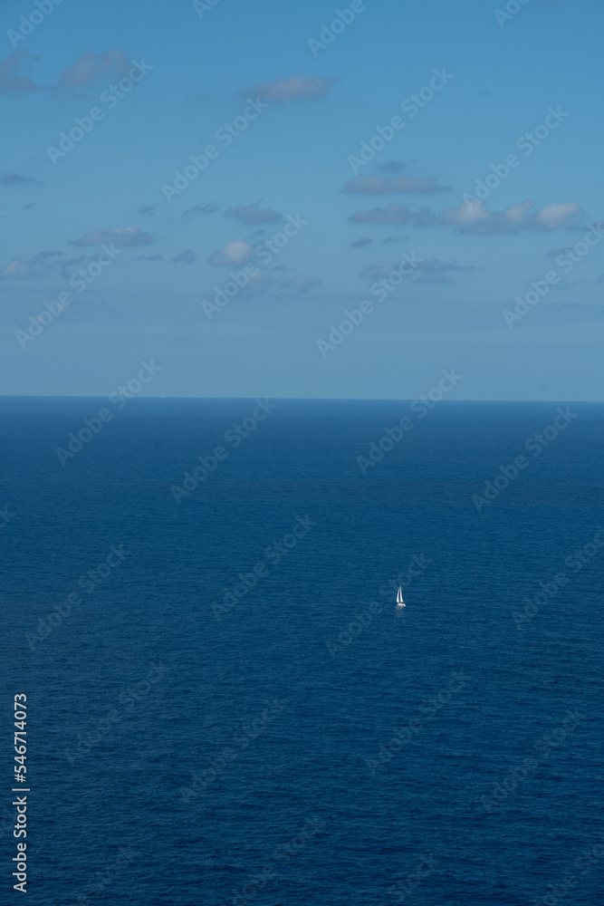 Obraz premium Tiny sailboat on the blue ocean