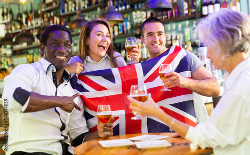 Happy diverse group celebrating Britain at a bar with beer