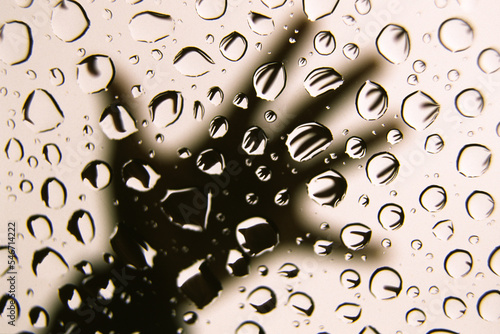 Water droplets refracting the image of a hand on the moon roof lass of  a car.