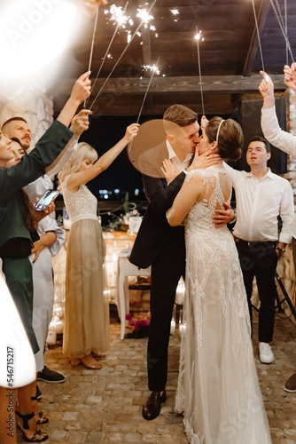 Guests with sparklers standing surround of newlyweds  photo