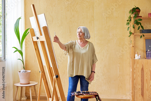 Elderly female artist measuring proportions of drawing photo