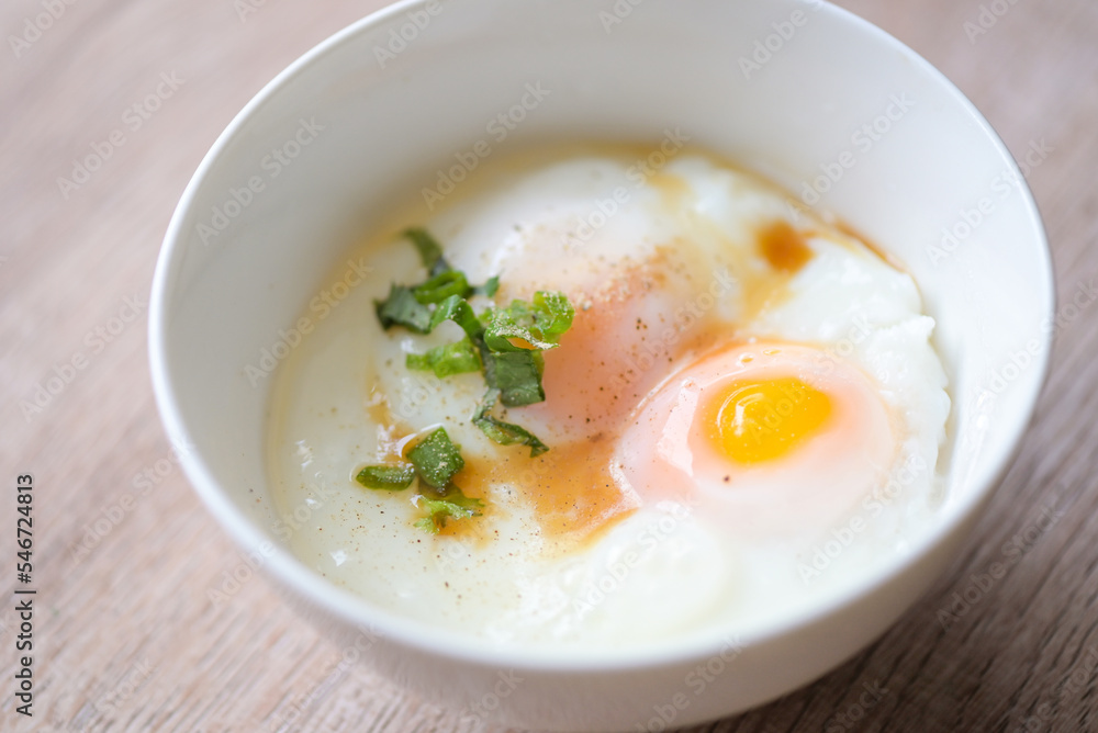 egg breakfast , soft-boiled eggs on white bowl with pepper, coriander on wooden table, Onsen tamago egg - egg microwave egg breakfast , soft-boiled eggs on white bowl with pepper, coriander on wooden table, Onsen tamago egg - egg microwave