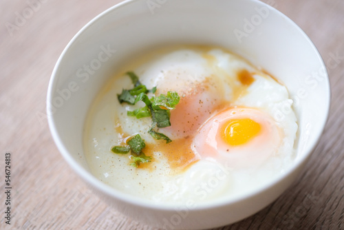 egg breakfast , soft-boiled eggs on white bowl with pepper, coriander on wooden table, Onsen tamago egg - egg microwave