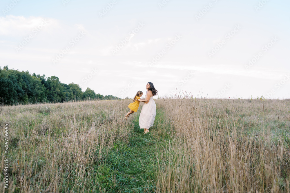 Mother and daughter walking in a field of grass Mother and daughter walking in a field of grass