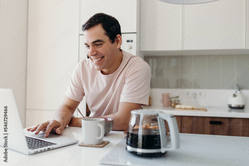 Happy middle aged male using netbook during breakfast Happy middle aged male using netbook during breakfast