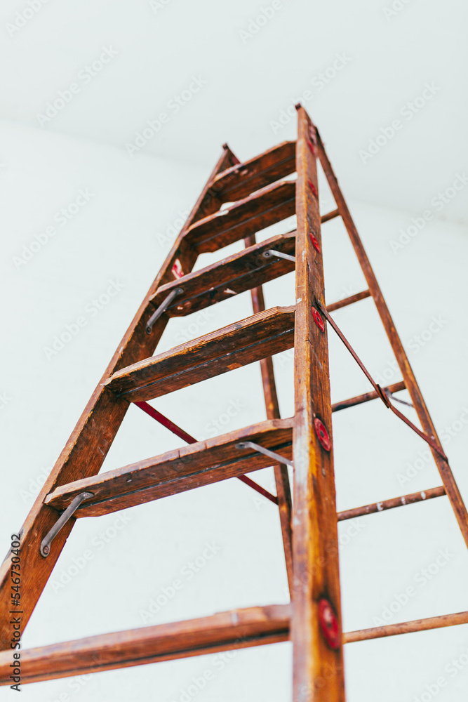 side view Antique wooden ladder in modern white brick warehouse side view Antique wooden ladder in modern white brick warehouse