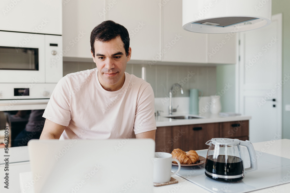 Middle aged man using laptop in kitchen Middle aged man using laptop in kitchen