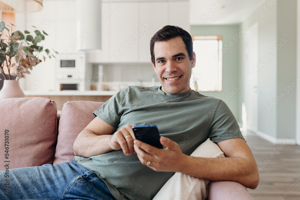 Cheerful mature man with smatrphone sitting on sofa Cheerful mature man with smatrphone sitting on sofa