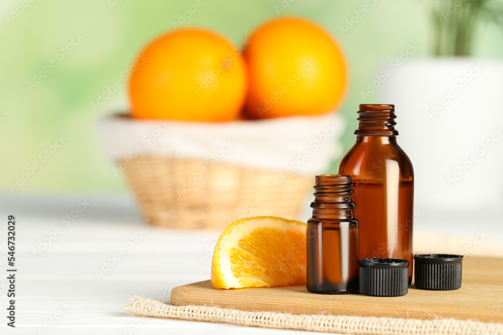 Bottles of essential oil and orange slice on white wooden table, space for text Bottles of essential oil and orange slice on white wooden table, space for text