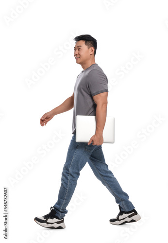 Man with laptop walking on white background © New Africa